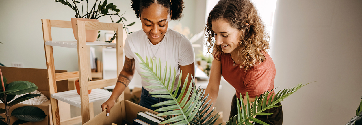 Deux femmes qui déménage avec des cartons et des plantes