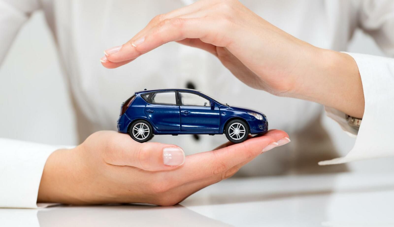 Deux mains portant une mini voiture