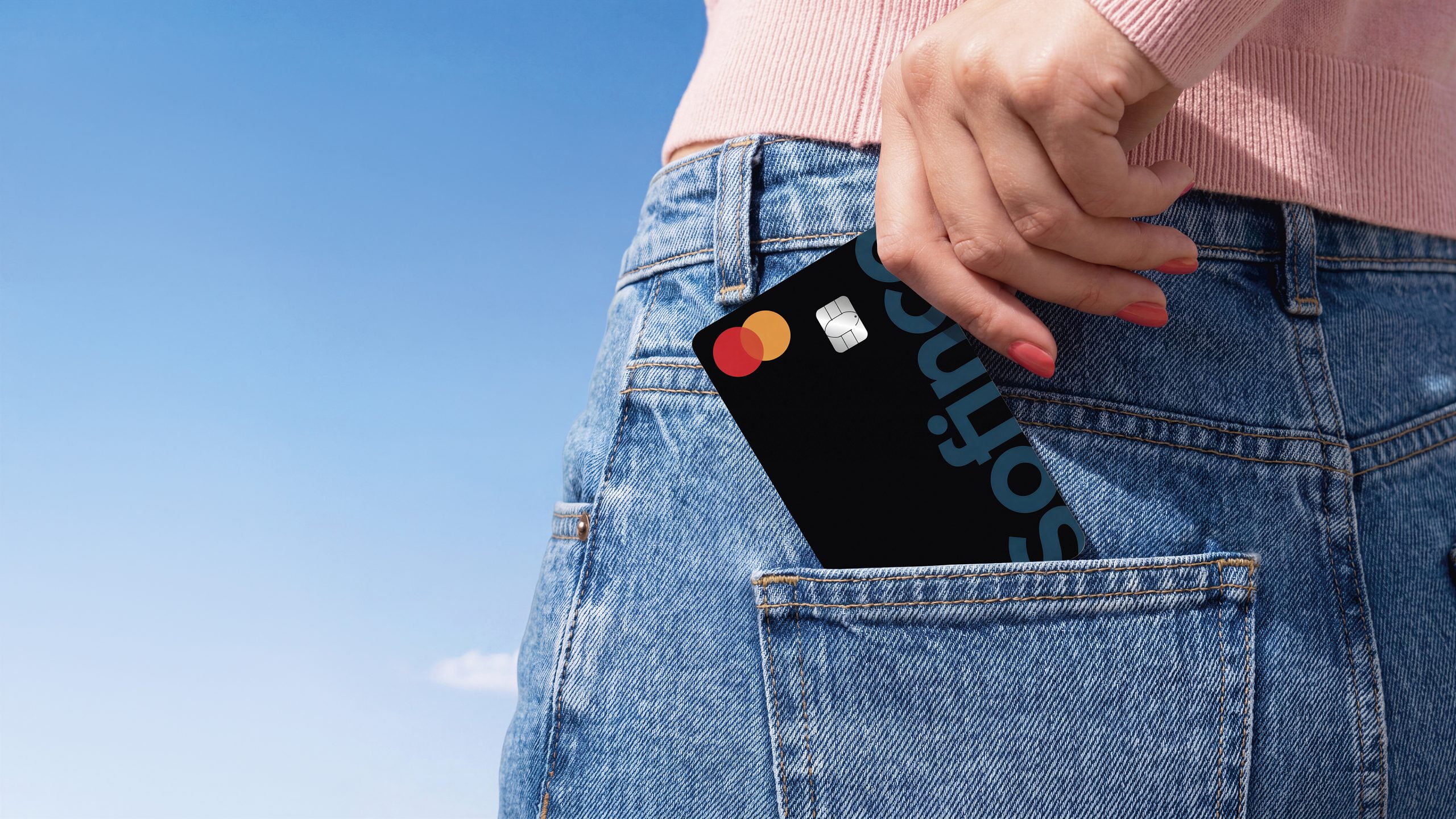 Main retirant une carte bancaire d’une poche de jean.