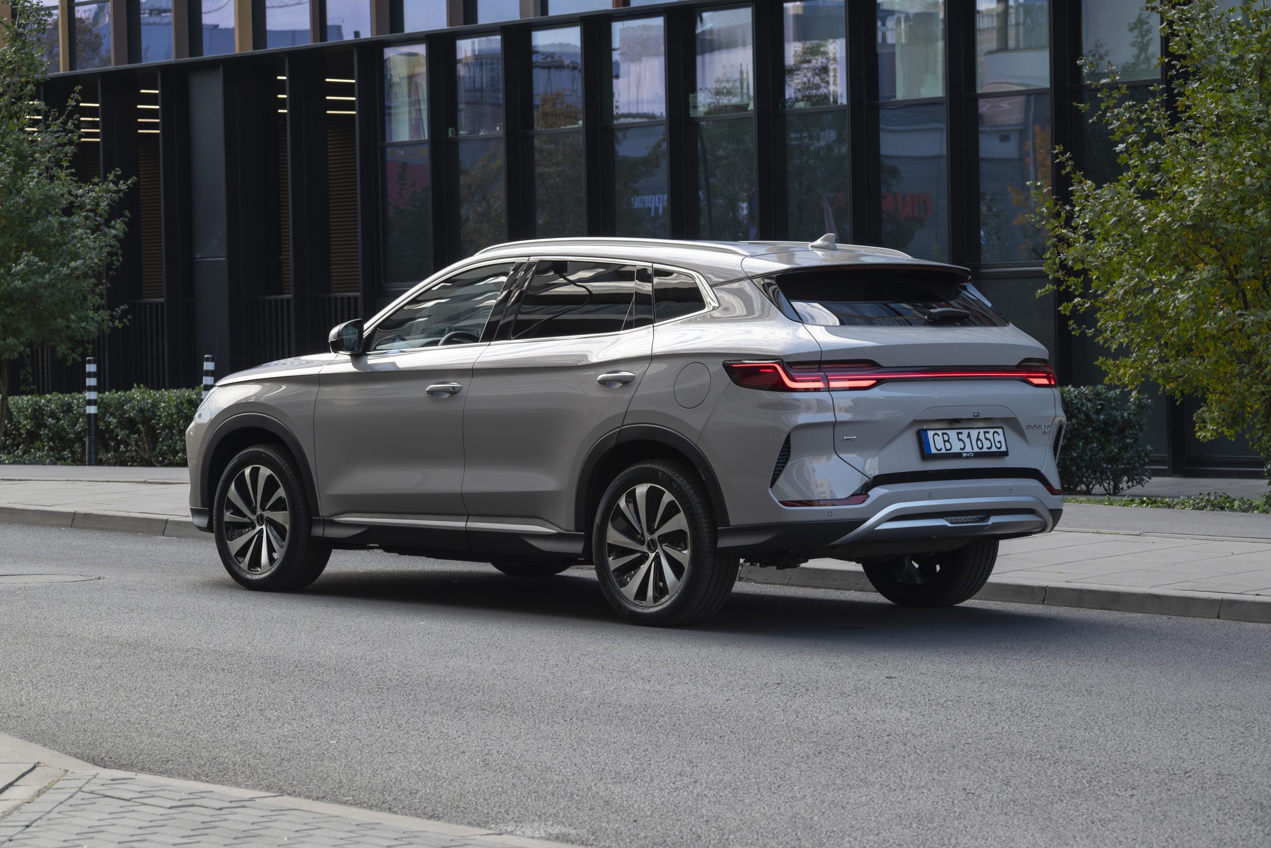 Véhicule gris roulant sur une route urbaine avec un bâtiment en fond