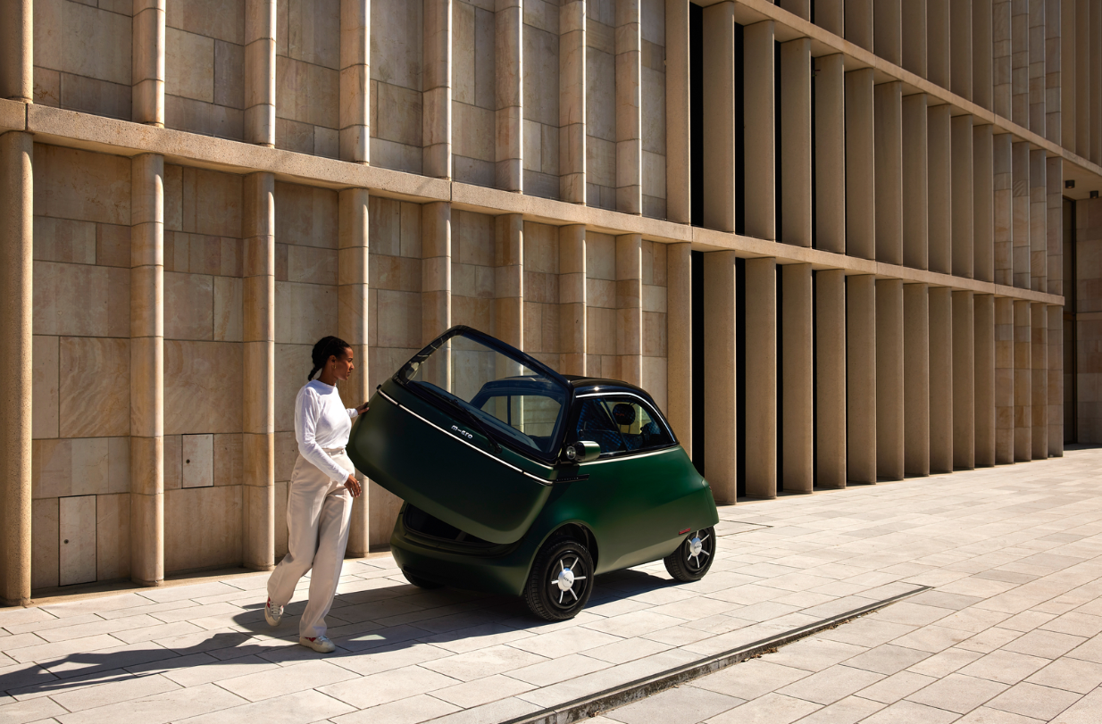 Petite voiture électrique garée devant un mur en bois à lames verticales.