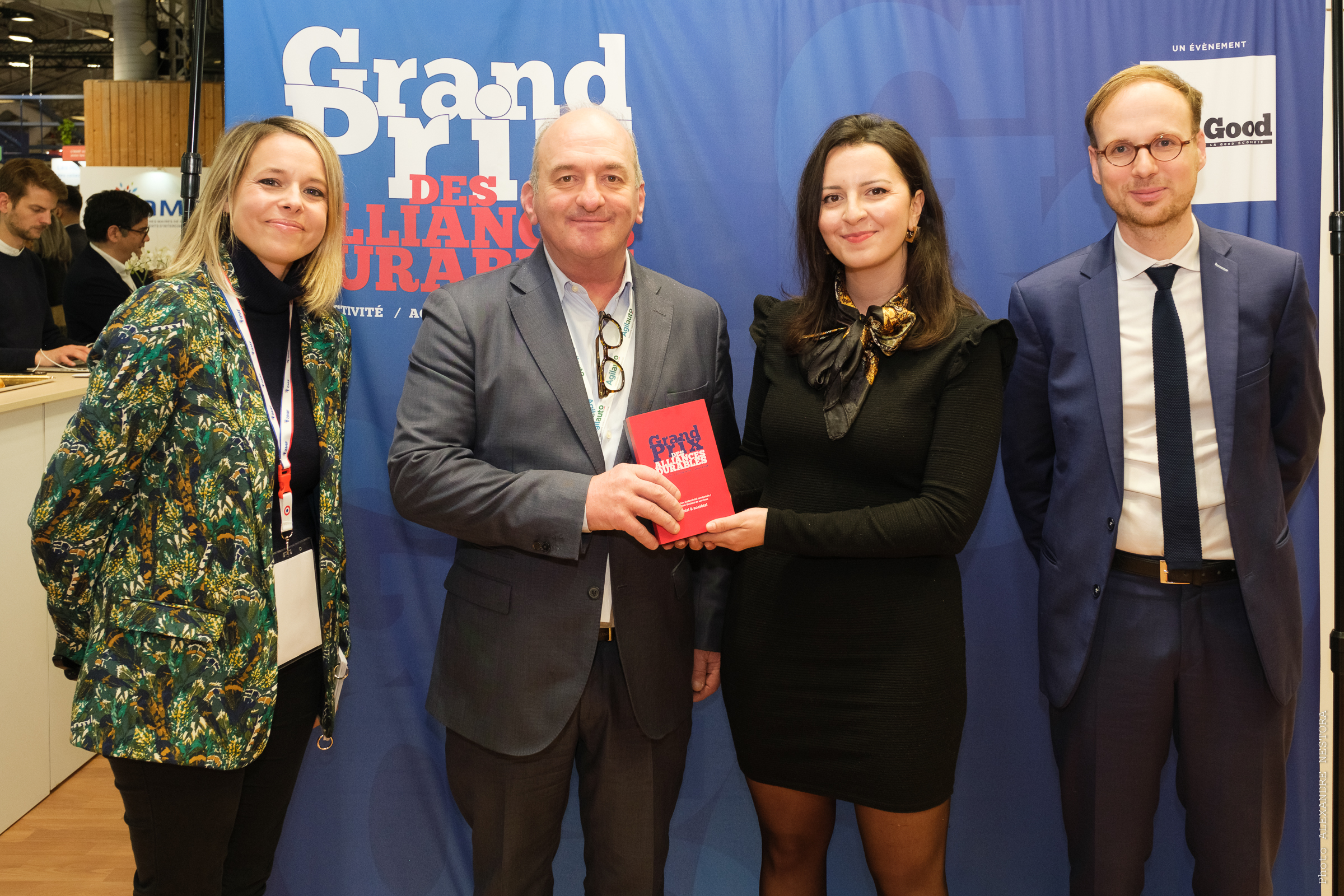 Quatre personnes souriantes fixant l'objectif incluant deux personnes qui tiennent un livre