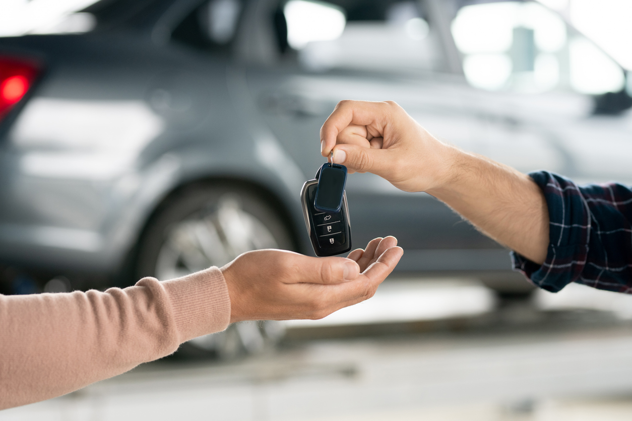 Remise de clés de voiture entre deux personnes devant un véhicule.