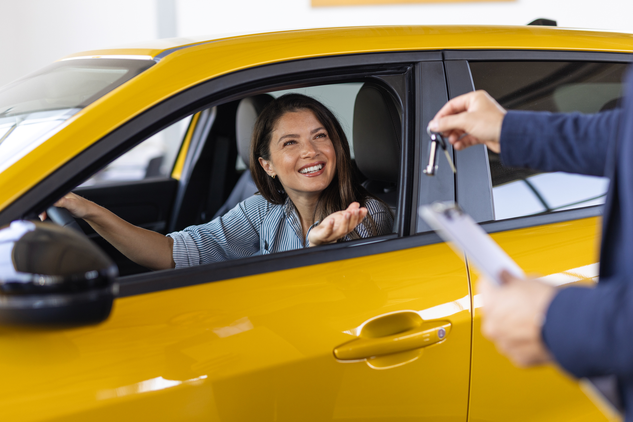 Remise de clés de voiture à une personne assise dans un véhicule jaune.