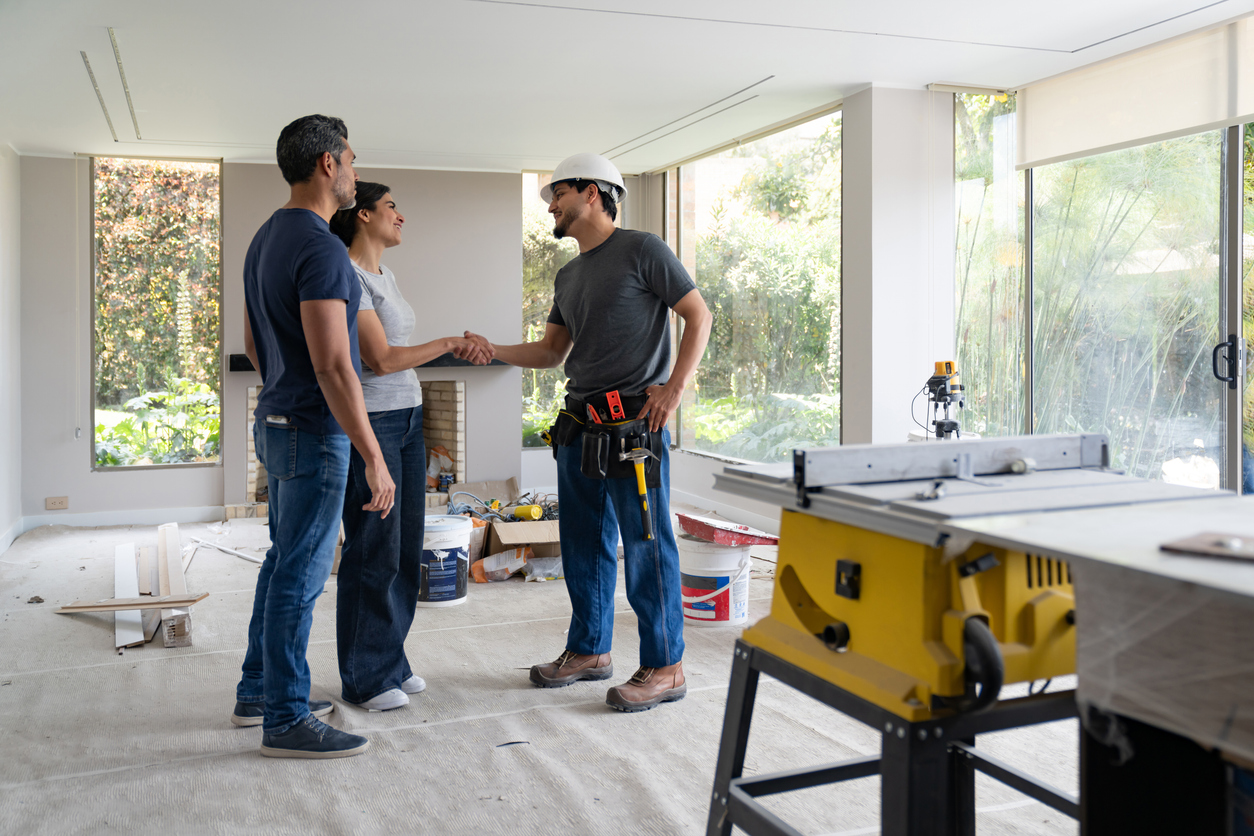Professionnel serrant la main de clients lors de travaux de rénovation intérieure.